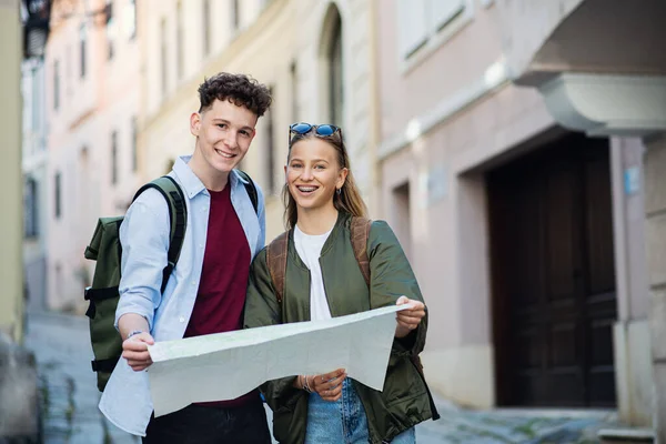 Young couple tourists travelers with map in city on holiday, looking at camera. — Stock Photo, Image