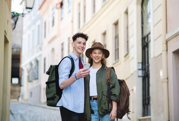 Jóvenes viajeros en pareja utilizando el teléfono inteligente en la ciudad de vacaciones, turismo. — Foto de Stock
