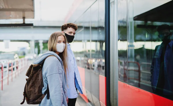 Pareja joven viajeros turísticos de vacaciones en la parada de autobús en la ciudad, concepto coronavirus. — Foto de Stock