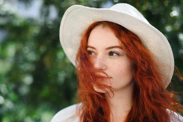 Close-up portrait of young woman with hat outdoors in city, headshot. — Photo