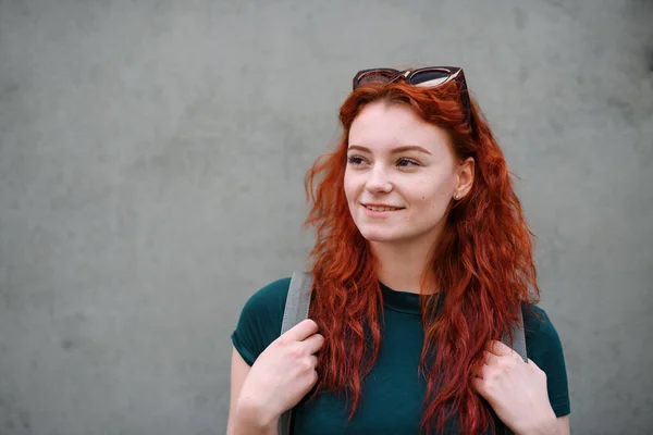 Porträt einer jungen Frau, die draußen vor grauem Hintergrund steht. Kopierraum. — Stockfoto