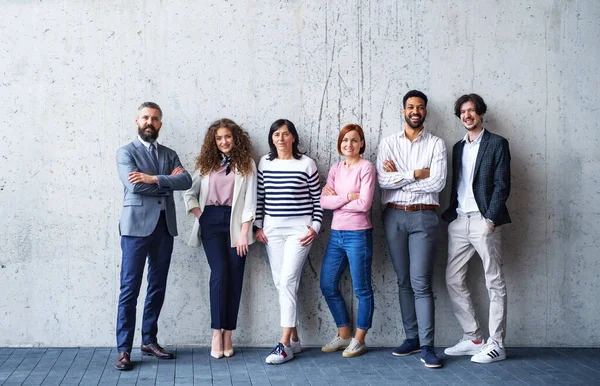 Porträtt av grupp entreprenörer som står mot betongvägg inomhus på kontoret, tittar på kameran. — Stockfoto
