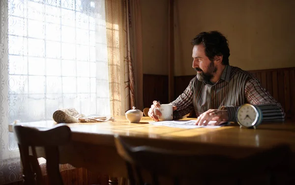 Portrait of unhappy poor mature man reading newspapers indoors at home, poverty concept. — Stock Photo, Image