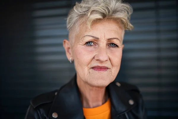 Portrait of senior woman standing against black backround, looking at camera. — Stock Photo, Image