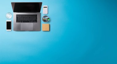 Üst kattaki ofis masası mavi arka planda dizüstü bilgisayarla çalışıyordu. Boşluğu kopyala.