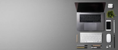 Üst kattaki ofis masası gri arka planda dizüstü bilgisayarla çalışıyordu. Boşluğu kopyala.