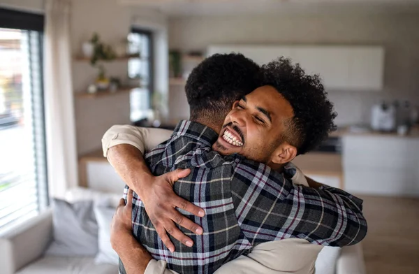 Joven feliz adulto hermanos en la cocina en el interior de casa, abrazos. —  Fotos de Stock