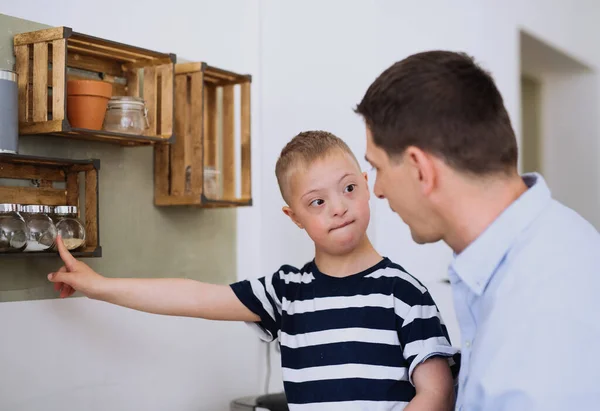 Pai com feliz para baixo filho síndrome dentro de casa na cozinha, cozinhar. — Fotografia de Stock