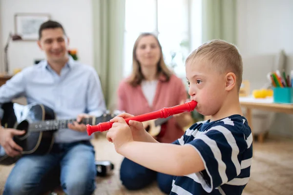 Alegre abajo síndrome chico con los padres tocando instrumentos musicales, riendo. — Foto de Stock