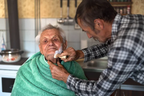 Porträt eines Mannes, der zu Hause einen älteren Vater rasiert. — Stockfoto