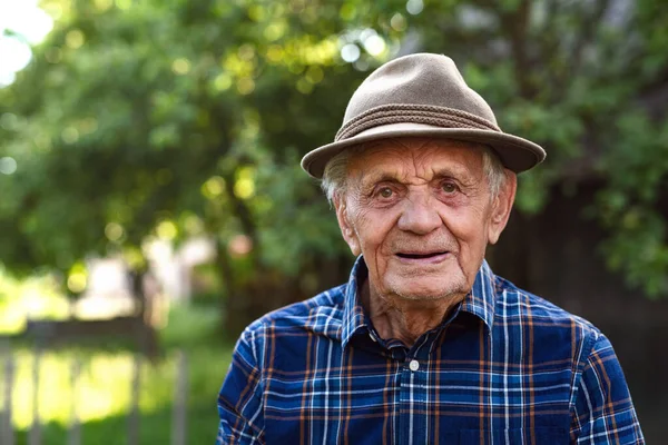 Porträt eines älteren Mannes, der draußen im Garten steht und in die Kamera blickt. — Stockfoto