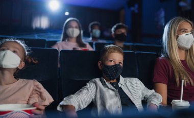 Anne ve küçük çocukları sinemada film izliyorlar, koronavirüs konsepti..
