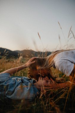 Kırsalda doğa yürüyüşüne çıkmış genç bir çift çimenlerde öpüşüyorlar..