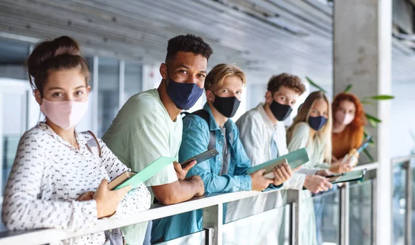 Estudiantes de la universidad de pie y mirando a la cámara en el interior, coronavirus y volver al concepto normal. — Foto de Stock