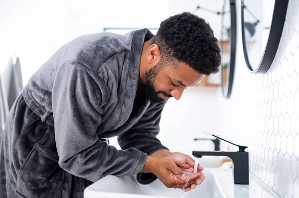 Jeune homme lavage visage à l'intérieur à la maison, matin ou soir concept de routine. — Photo