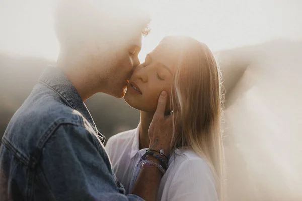 一对年轻夫妇在日落时分在野外散步，亲吻着. — 图库照片