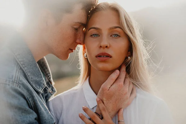 Pareja joven en un paseo por la naturaleza al atardecer en el campo, abrazos. —  Fotos de Stock