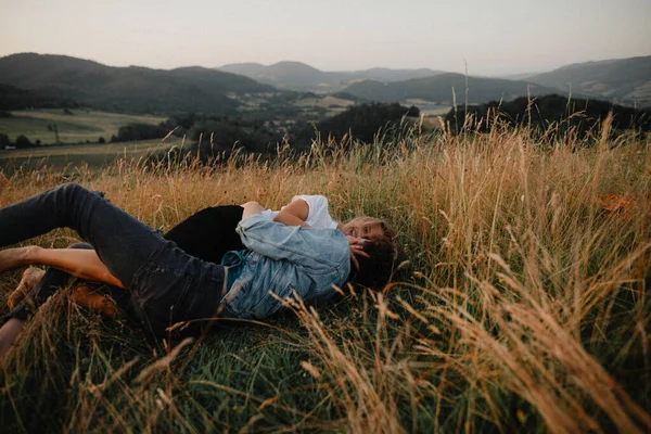 Jong stel op een wandeling in de natuur op het platteland, liggend in gras plezier hebben. — Stockfoto