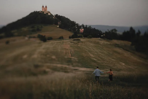 Widok z tyłu młoda para spacerujących w przyrodzie o zmierzchu na wsi, Bańska Stiavnica na Słowacji. — Zdjęcie stockowe