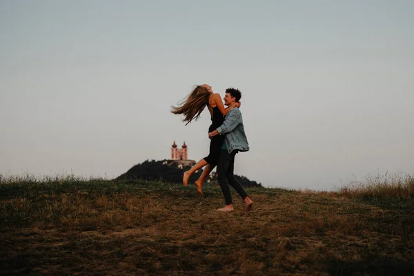 Unga par på en promenad i naturen i skymningen på landsbygden, har kul kramas. — Stockfoto