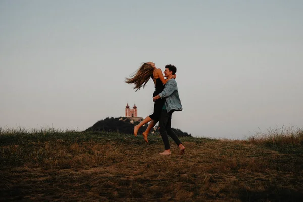 Pareja joven en un paseo por la naturaleza al atardecer en el campo, divirtiéndose abrazándose. —  Fotos de Stock