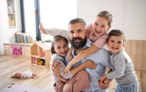 Far med tre döttrar inomhus hemma, tittar på kameran. — Stockfoto