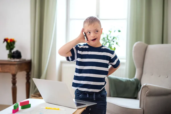 Happy down syndrom son inomhus, med hjälp av smartphone. — Stockfoto