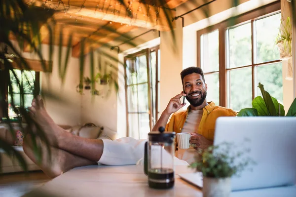 Joven con portátil y café trabajando en interiores, concepto de oficina en casa. — Foto de Stock