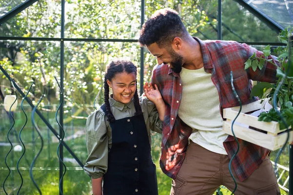 Glücklicher junger Vater mit kleiner Tochter arbeitet draußen im Garten, Gartenarbeit und Gewächshauskonzept. — Stockfoto