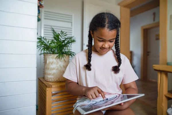 Feliz niña pequeña con la tableta en el interior de casa, jugando. — Foto de Stock