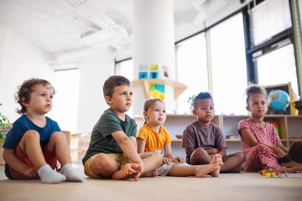Group of small nursery school children sitting on floor indoors in classroom. — Stock Photo, Image