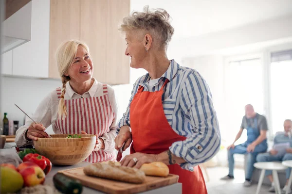 Gruppo di amici anziani che fanno festa in casa, cucinano e parlano. — Foto Stock