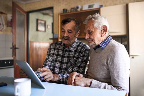 Evdeki masada tablet kullanarak oturan yaşlı bir adamın portresi.. — Stok fotoğraf