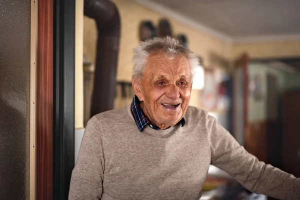 Portret van een bejaarde man die thuis staat te lachen. — Stockfoto