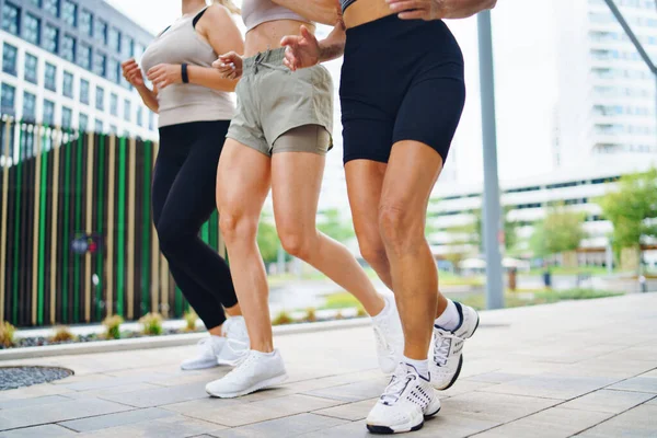 Grupo de mujeres irreconocibles haciendo ejercicio al aire libre en la ciudad, corriendo. — Foto de Stock