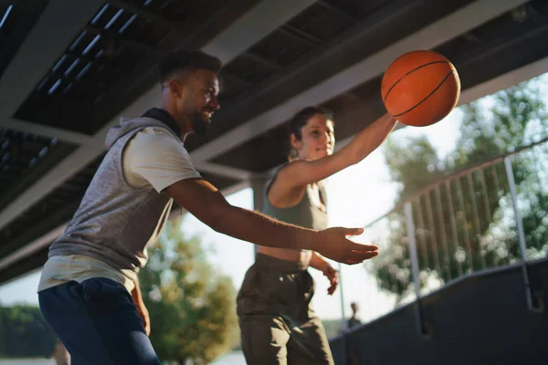 Férfi és nő barátok kosárlabdáznak a szabadban a városban. — Stock Fotó