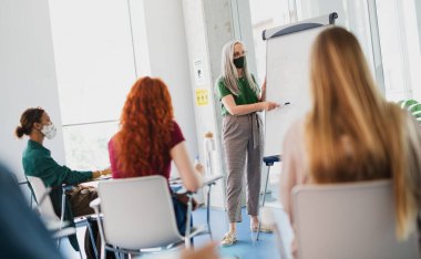Üniversite öğrencilerinin, öğretmenlerinin kapalı alanlarda, koronavirüslerde ve normal konsepte geri dönmelerinin arka görüntüsü..