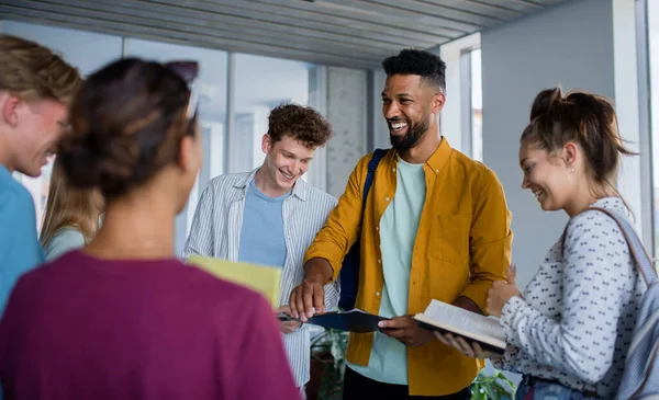 Groep universiteitsstudenten die binnen in de gang staan te praten en lachen. — Stockfoto