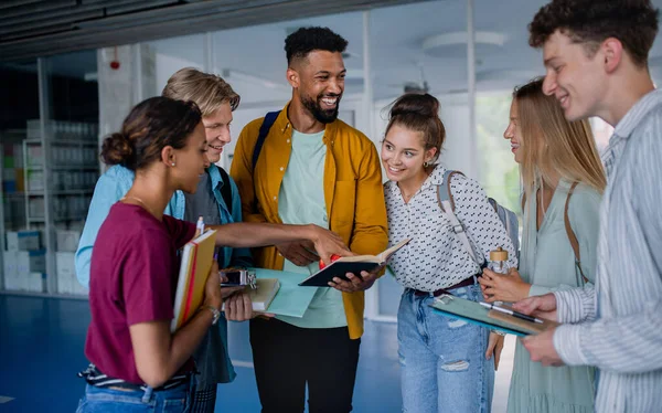 Grupo de estudiantes universitarios de pie en el pasillo interior, hablando y riendo. — Foto de Stock