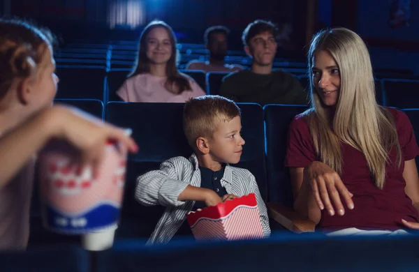 映画の中で幸せな小さな子供たちと母,映画を見て、ポップコーンを食べる. — ストック写真