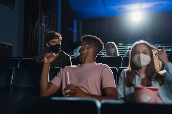 Jovens sentados e cumprimentando no cinema, conceito de coronavírus. — Fotografia de Stock