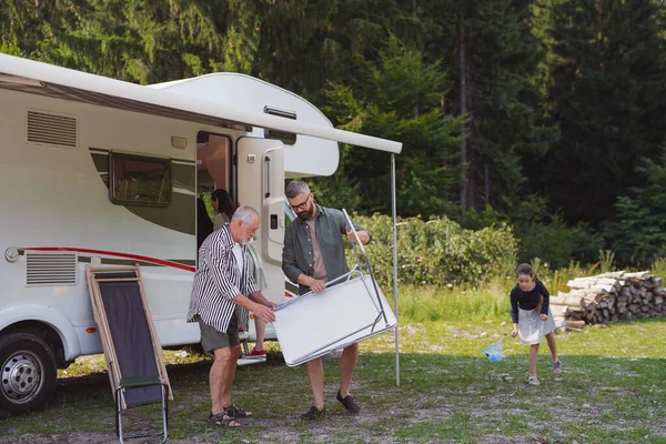 Multi-generation family unpacking and talking by car, caravan holiday trip. — Stock Photo, Image