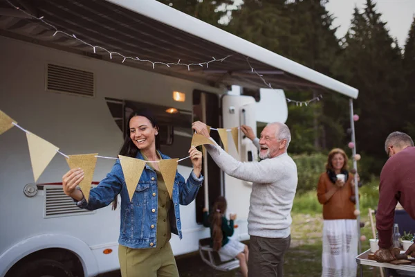 Multi-generation family preparing party by car outdoors in campsite, caravan holiday trip. — Stock Photo, Image