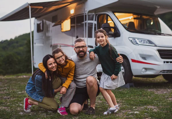 Familia feliz mirando la cámara al aire libre al atardecer, viaje de vacaciones en caravana. — Foto de Stock