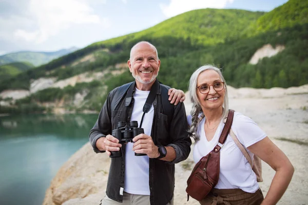 Feliz pareja mayor en viaje de senderismo en vacaciones de verano, usando prismáticos. — Foto de Stock