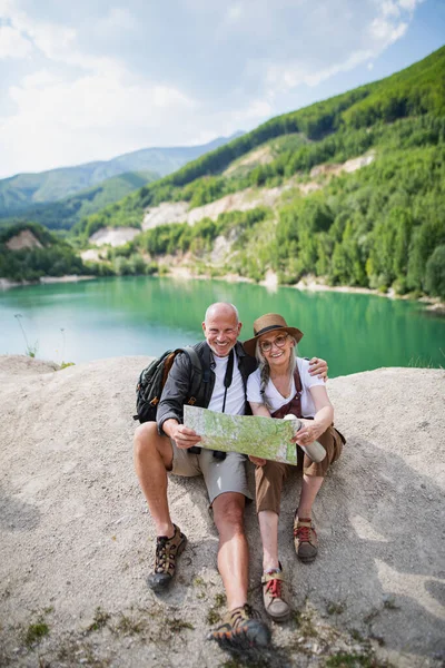 Feliz pareja de ancianos en viaje de senderismo en vacaciones de verano, utilizando el mapa. — Foto de Stock