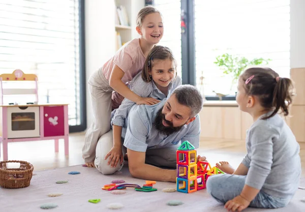 Vader met drie dochters thuis, spelend op de vloer. — Stockfoto