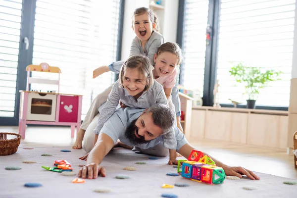 Far med tre döttrar inomhus, leker på golvet. — Stockfoto