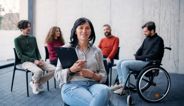 Rådgivare med män och kvinnor som sitter i cirkel under gruppterapi, tittar på kameran. — Stockfoto