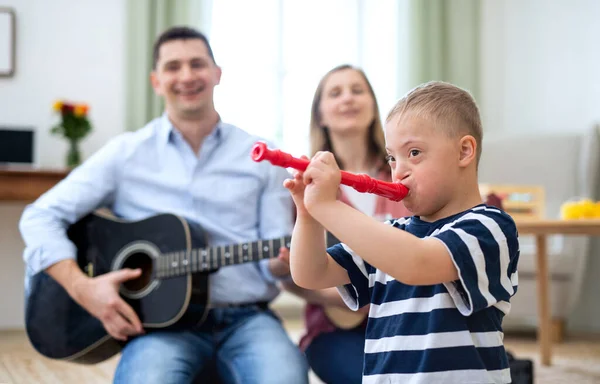 Alegre abajo síndrome chico con los padres tocando instrumentos musicales, riendo. — Foto de Stock
